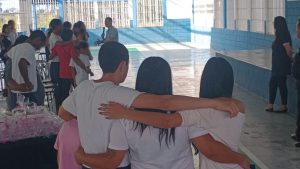 Imagem retrata mãe abraça com seus filhos de costas para o fotógrafo 