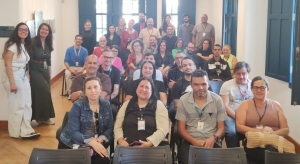 Foto mostra cerca de 30 adultos sentados na plateia do museu, entre homens e mulheres, além de algumas pessoas em pé. A maioria sorri