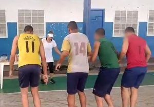 Fotografia retrata jovens fazendo passos dança durante oficina. Os jovens estão de costas e são orientados por uma professora
