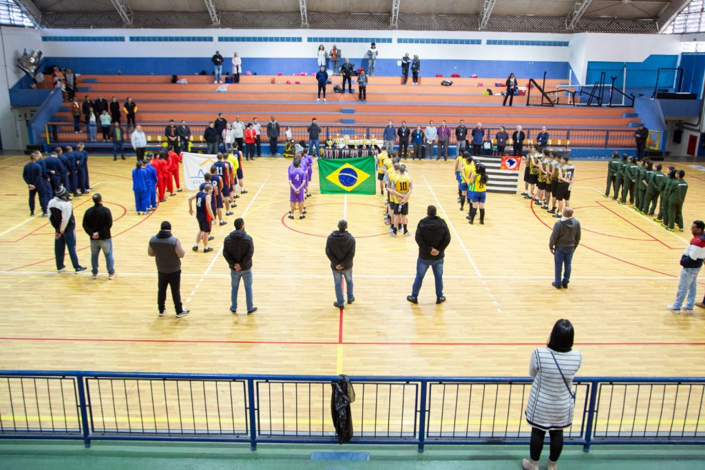Atletas perfilados ao redor da bandeira do Brasil durante a cerimônia de premiação do torneio de basquete da Fundação CASA