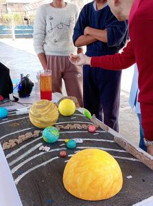 Fotografia mostra maquete feita por adolescentes, sobre o sistema solar. Itens retratam os planetas e suas órbitas